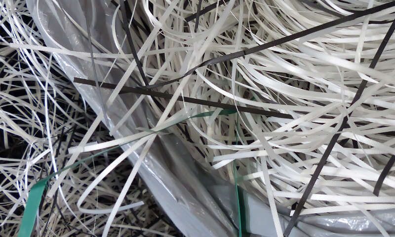 Eine graue Plastiktüte, Kabelbinder aus Polypropylen-Plastik in weißer und schwarzer Farben, Umreifungsbänder aus Kunststoff auf dem Gelände der Xpress Paper GmbH. Dieser Plastik-Abfall wurde entsorgt, sortiert und wartet auf Weiterverarbeitung.