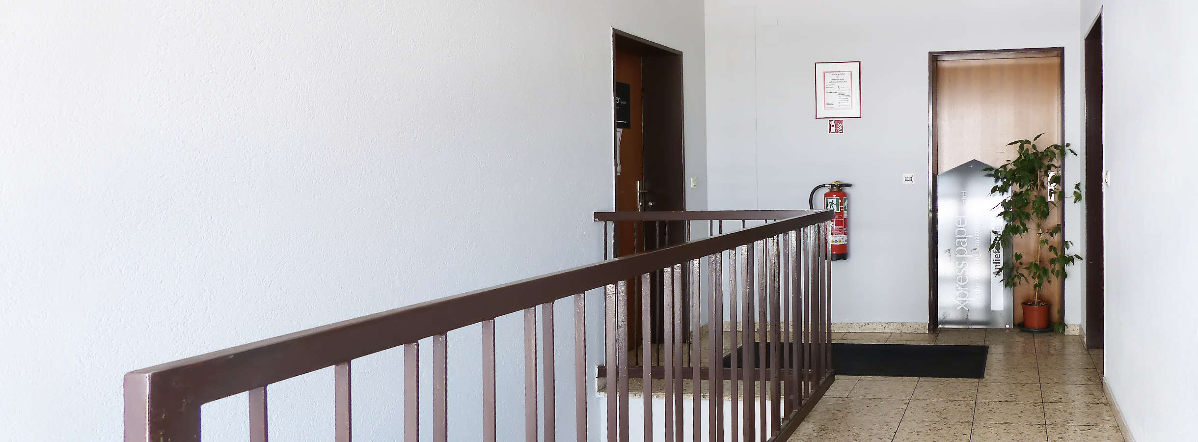 Flur im Treppenhaus des Bürogebäudes vom Recyclingunternehmen Xpress Paper. Links, hinter dem Geländer ist die Treppe zum Ausgang. Vorn sind drei Türen zu den Büroräumen für Mitarbeiter und Kundenbesuche des Entsorgungsbetriebs bei Frankfurt/Main.